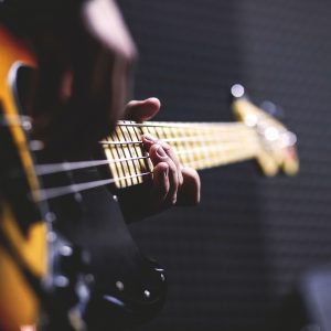person playing sun burst electric bass guitar in bokeh 96380